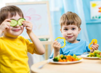 Pienet lapset syövät kasviksia, ja toinen heistä on tehnyt kurkunsiivuista silmälaput.