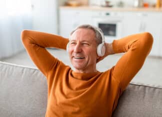 iloinen keski-ikäinen mies kuuntelee sohvalla musiikkia
