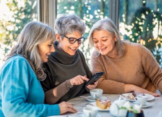 kolme iloista keski-ikäistä naista viettävät aikaa kahvilassa