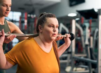 ylipainoinen nainen harjoittelee kuntosalilla