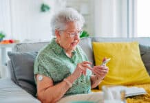 iäkäs-diabetesta-sairastava-nainen-istuu-sohvalla- ja-tutkii-puhelintaan